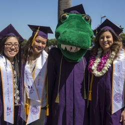 3 graduating friends posing with the SF State mascot at graduation